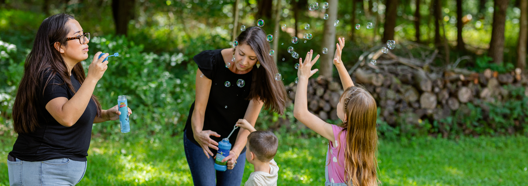 Moms blow bubbles outside with children